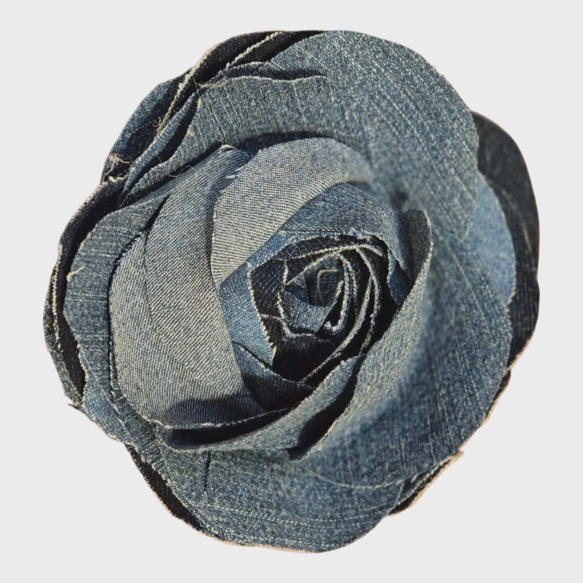 Close-up of a decorative fabric rose in shades of gray and black against a white background